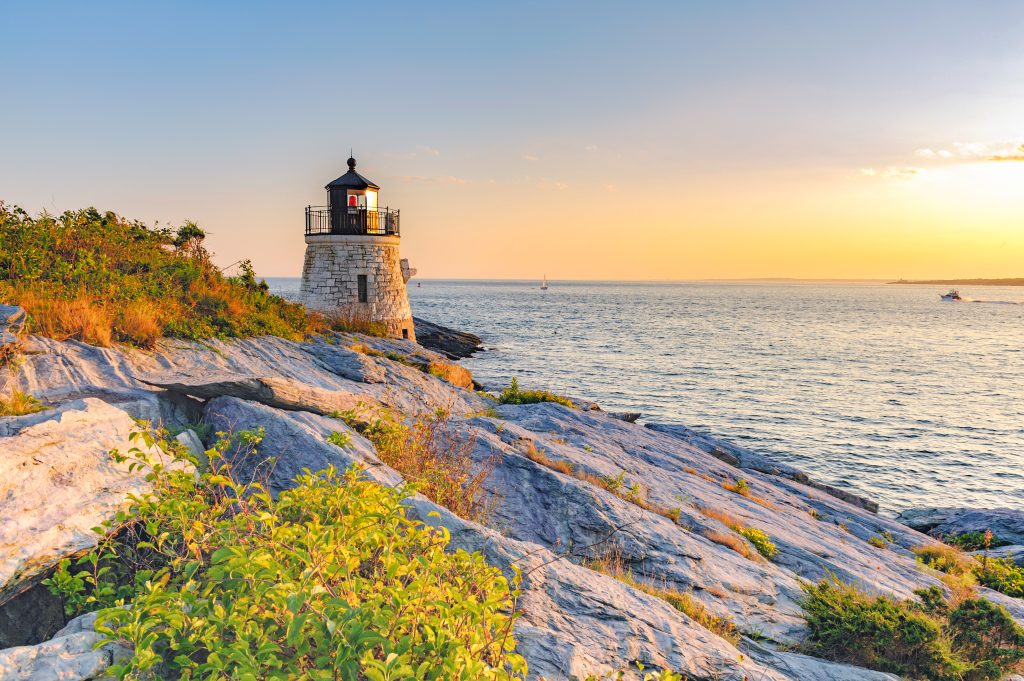 Castle Hill Lighthouse at twilight during the golden hour just before sunset, Newport, Rhode Island, USA, Labor Day Weekend, September 2009. The beautiful granite tower, completed in 1890, is built right into the cliff face. The original beacon was a kerosene-powered fifth-order Fresnel lens, which was replaced in 1899, and again in 1957 by the current modern plastic lens when the last lighthouse keeper left and Castle Hill light was automated in 1957. With its red beacon, Castle Hill light house is still an active navigational aids for ships in Narragansett Bay heading toward Providence and Newport, RI. The lighthouse stands on land sold to the United States government for $1.00. Although the tower is not open to the public, you may walk right up to it across the cliffs.
